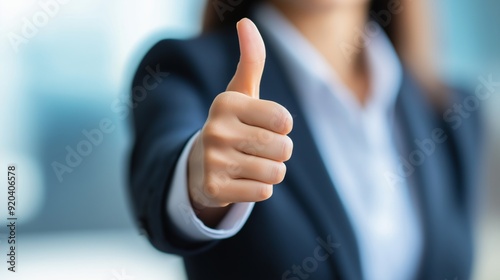 Businesswoman gives a thumbs up gesture in a bright office setting during the day.