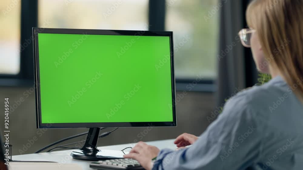 Young Woman Working In Office On Desktop Computer with Green Screen Mock Up Display. Over the Shoulder- Close-up of Monitor With Green Screen Chromakey Young Woman Working In Office On Desktop Computer with Green Screen Mock Up Display. Over the Shoulder- Close-up of Monitor With Green Screen Chromakey