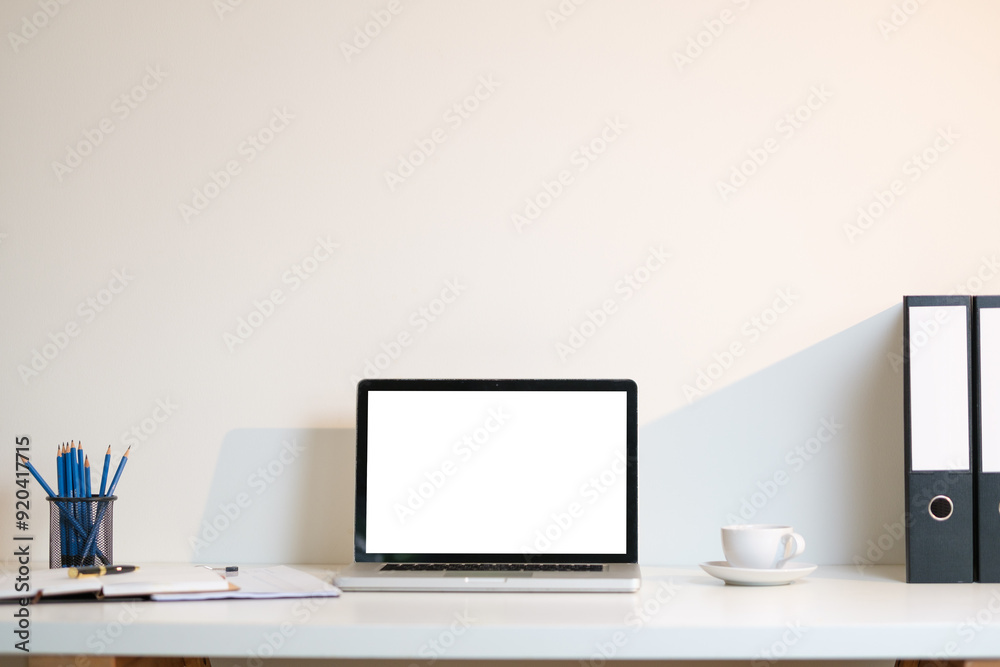Minimalist and organized workspace with a clean, modern aesthetic At the center of the desk is a laptop with a blank white screen, ready for use. Minimalist and organized workspace with a clean, modern aesthetic At the center of the desk is a laptop with a blank white screen, ready for use.