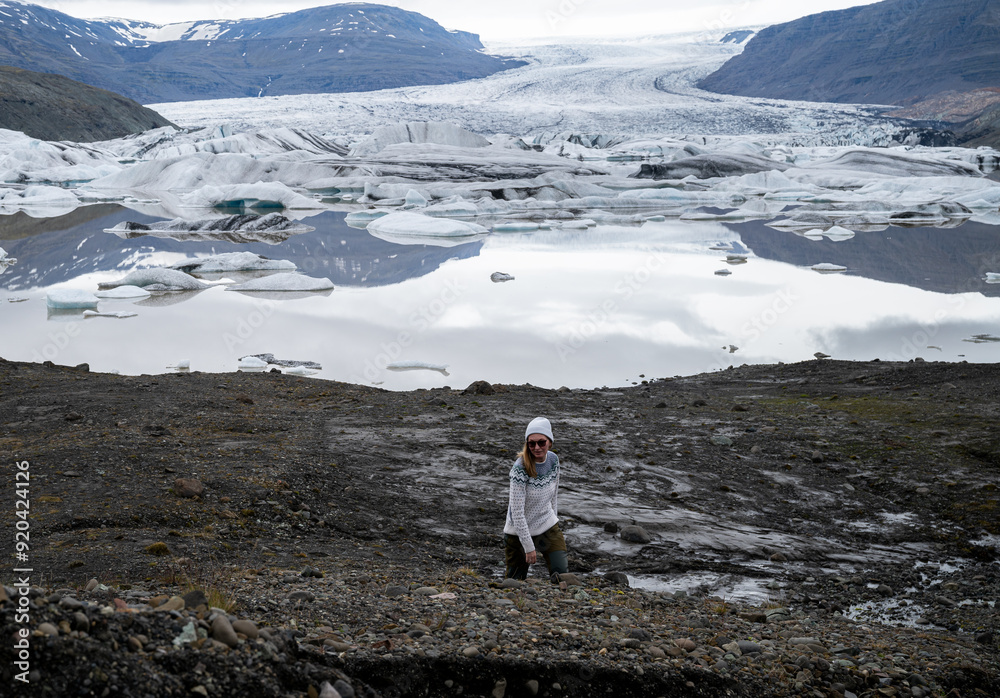 young woman walks next to a glacier in Iceland young woman walks next to a glacier in Iceland