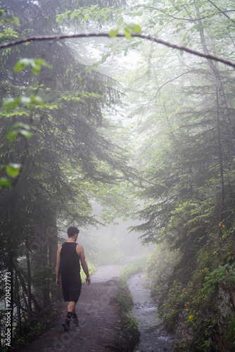 The man is walking along the forest in the fog