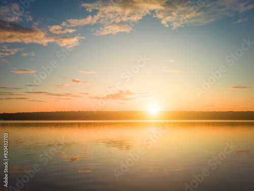 Sunrise or sunset on a lake or river with dramatic cloudy sky reflection in the water in summer.