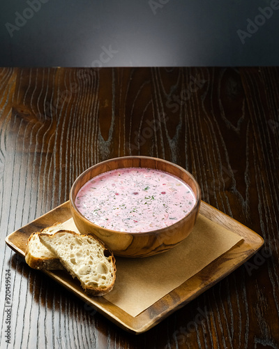 Traditional Russian Svekolnik Beet Soup in Wooden Bowl with Bread Slices on Rustic Table. photo