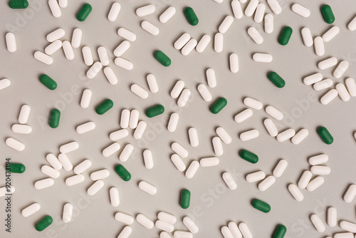 Many white pills and green tablets from above on a light background. Medicines flat lay. Background of a big amount of  tablets.