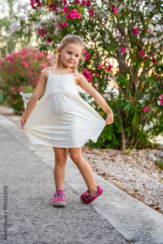 Portrait of little girl in white dress happy smiling and dancing on blooming park background in Croatia Portrait of little girl in white dress happy smiling and dancing on blooming park background in Croatia