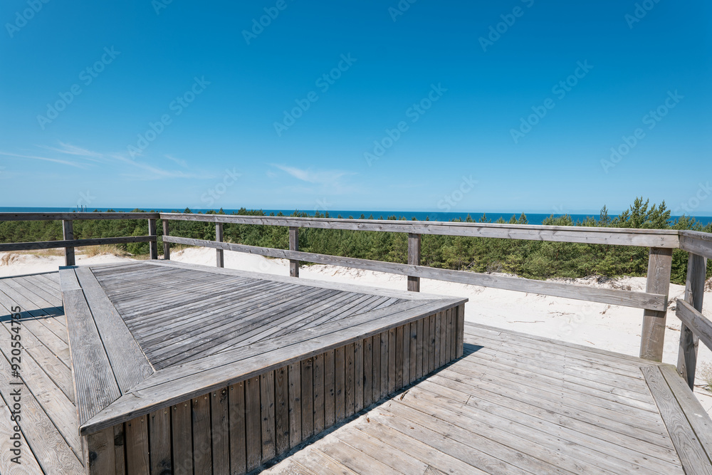 Viewpoint of the Dunes in Lubiatowo. A wooden viewing platform covered with gray boards. The Baltic Sea in the distance