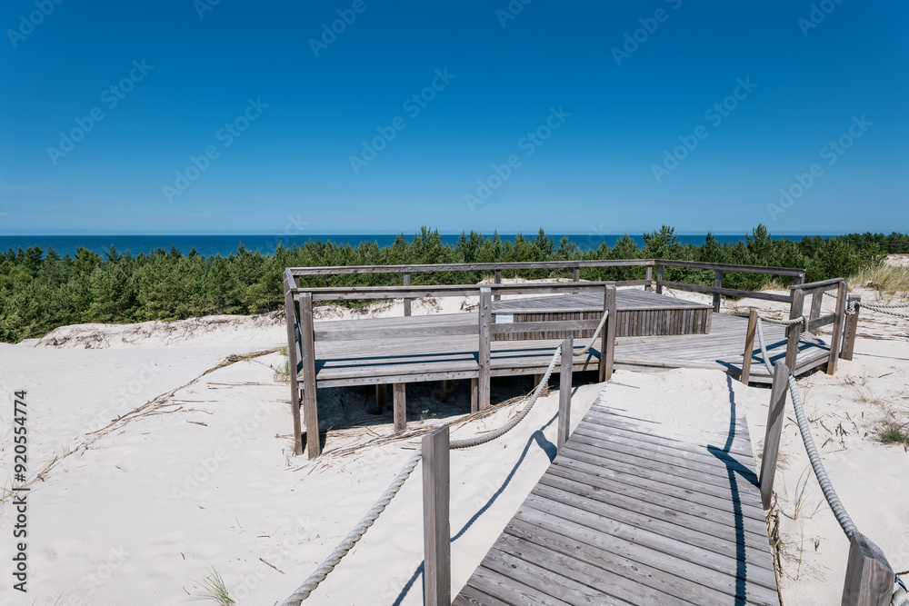 Viewpoint of the Dunes in Lubiatowo. A wooden viewing platform covered with gray boards. The Baltic Sea in the distance