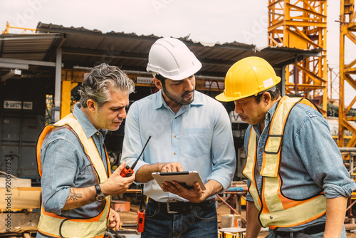 Professional construction engineer workers team working cooperate together consulting looking at tablet screen at project building construction site. photo