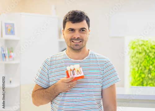 cute kid boy child, woman or man holding dental implant mockup, artificial tooth roots into jaw canal. dental treatment concept.smiling people in dental office.family in dentistry.teeth model on white photo