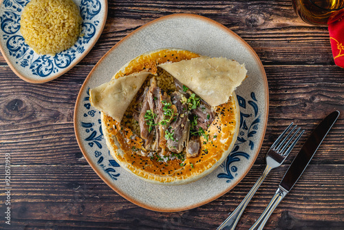 Lamb shank with bulgur pilaf and dough-covered top from traditional Turkish cuisine photo