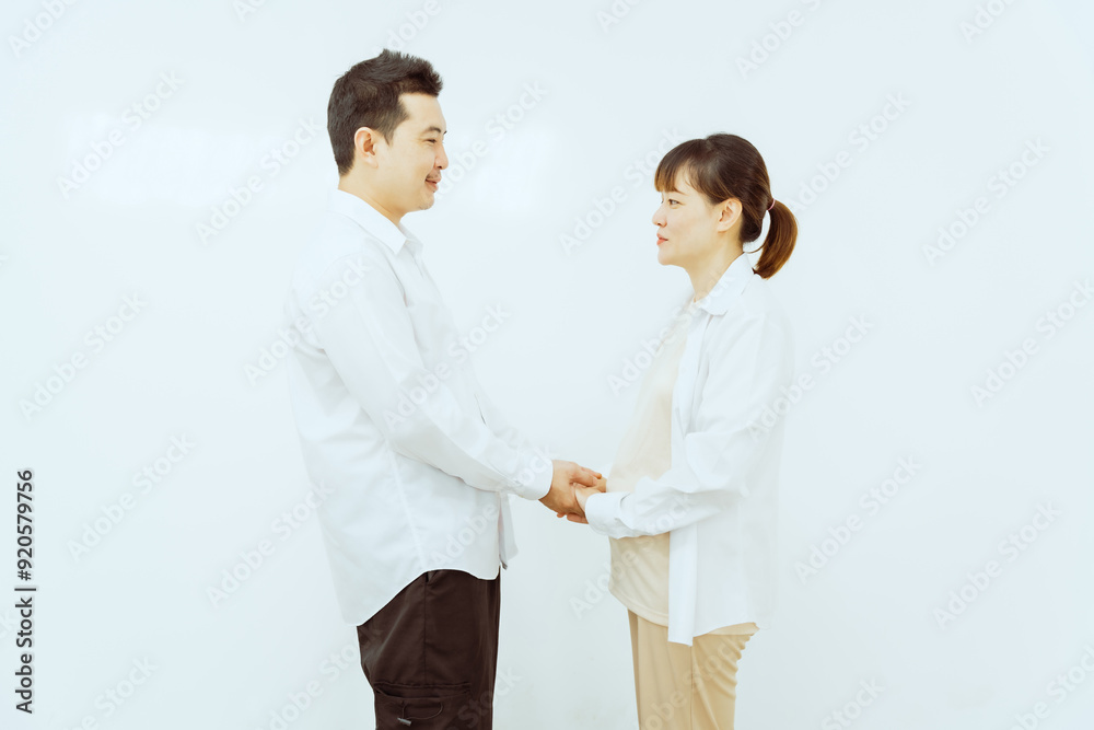 A middle-aged Asian couple, with the woman being pregnant, shares a loving embrace, smiling with happiness and anticipation for their soon-to-arrive baby, symbolizing family togetherness and joy. A middle-aged Asian couple, with the woman being pregnant, shares a loving embrace, smiling with happiness and anticipation for their soon-to-arrive baby, symbolizing family togetherness and joy.