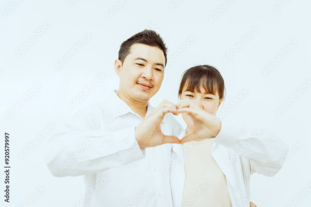 A middle-aged Asian couple, with the woman being pregnant, shares a loving embrace, smiling with happiness and anticipation for their soon-to-arrive baby, symbolizing family togetherness and joy. A middle-aged Asian couple, with the woman being pregnant, shares a loving embrace, smiling with happiness and anticipation for their soon-to-arrive baby, symbolizing family togetherness and joy.