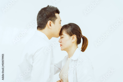 A middle-aged Asian couple, with the woman being pregnant, shares a loving embrace, smiling with happiness and anticipation for their soon-to-arrive baby, symbolizing family togetherness and joy.