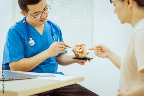 A male Asian pediatrician in a white lab coat conducts a prenatal checkup for a middle-aged pregnant woman, focusing on maternal and fetal health, offering expert care and guidance. photo