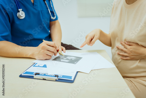 A male Asian pediatrician in a white lab coat conducts a prenatal checkup for a middle-aged pregnant woman, focusing on maternal and fetal health, offering expert care and guidance. photo