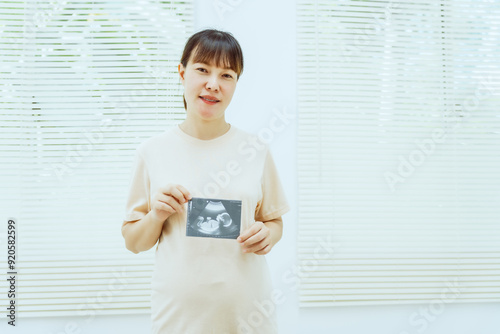 A middle-aged pregnant Asian woman is isolated on a white background, highlighting her maternity with a focus on prenatal care, showcasing the beauty and anticipation of her growing belly.