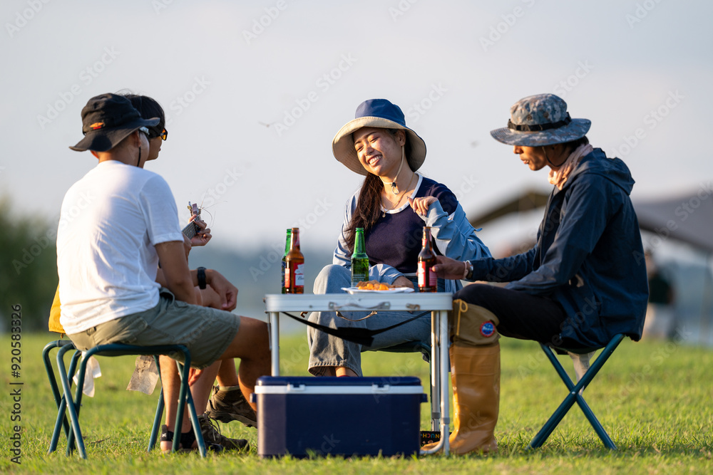 Three people are sitting around a picnic table with drinks and food Three people are sitting around a picnic table with drinks and food