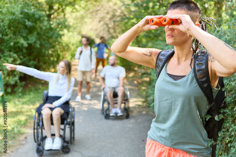 Obraz premium Group of friends on outdoor adventure, woman using binoculars, inclusion of persons with disabilities