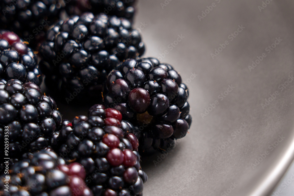 Black bramble berries in grey ceramic plate. Fresh juicy organic blackberries. Healthy ingredient. Macro