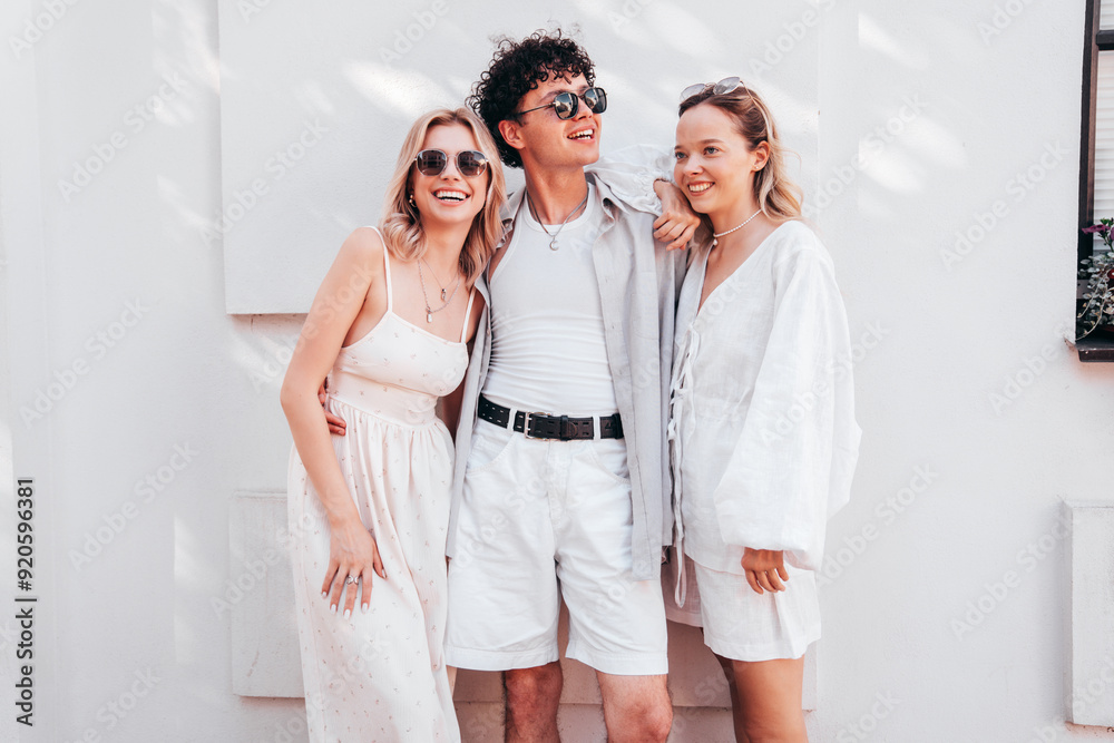Young three stylish friends posing in the street. Fashion man and two cute female dressed in casual summer clothes. Smiling models having fun. Cheerful women and guy outdoors, in sunny day, sunglasses Young three stylish friends posing in the street. Fashion man and two cute female dressed in casual summer clothes. Smiling models having fun. Cheerful women and guy outdoors, in sunny day, sunglasses