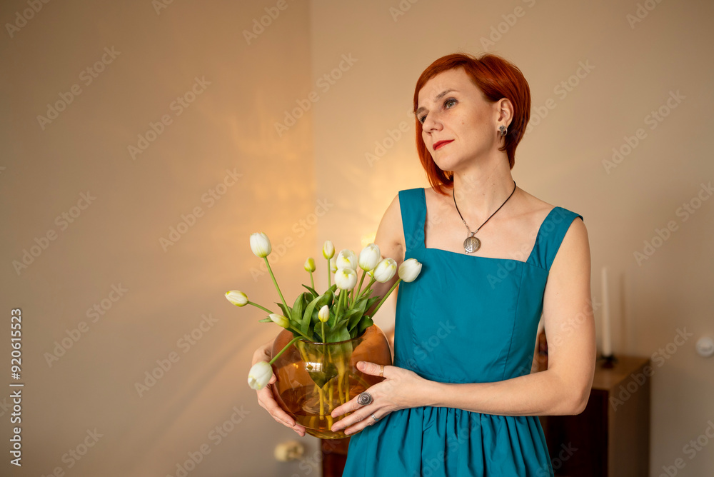 Beautiful adult woman with red hair short haircut holding present flowers tulip bouquet. Home decorating with flowers Beautiful adult woman with red hair short haircut holding present flowers tulip bouquet. Home decorating with flowers