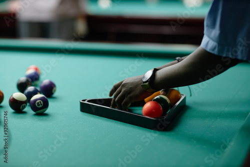 Fényképezés Hand arranging colorful billiard balls on table with focused precision, watch vi
