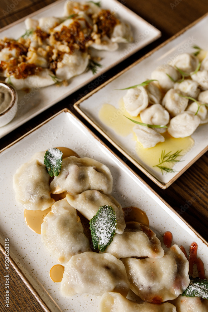 Delicious juicy dumplings with fragrant herbs and cracklings, served with buttery sauce and sour cream in a beautiful dish on a wooden table in a cozy, charming restaurant Delicious juicy dumplings with fragrant herbs and cracklings, served with buttery sauce and sour cream in a beautiful dish on a wooden table in a cozy, charming restaurant
