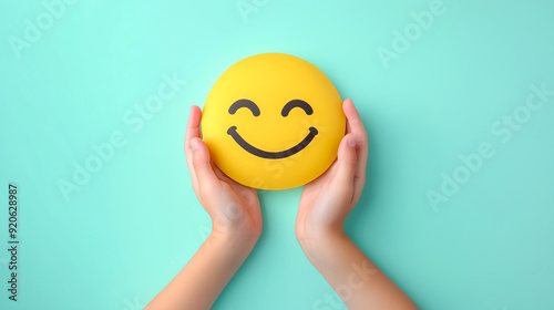 Children's hands holding positive smiley face isolated on light green background. Child health and protection concept. photo