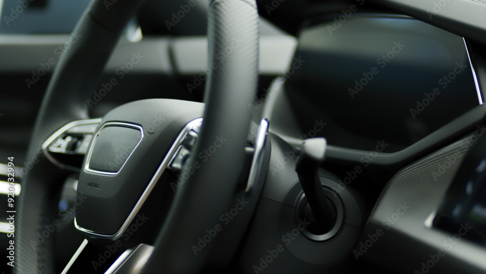 Close-up of a steering wheel in a modern electric car, featuring a sleek dashboard and advanced technology. Ideal for illustrating the elegance and innovation in today’s automotive industry. Close-up of a steering wheel in a modern electric car, featuring a sleek dashboard and advanced technology. Ideal for illustrating the elegance and innovation in today’s automotive industry.