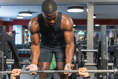 Black fitness trainer helping another man at the gym with the barbell photo