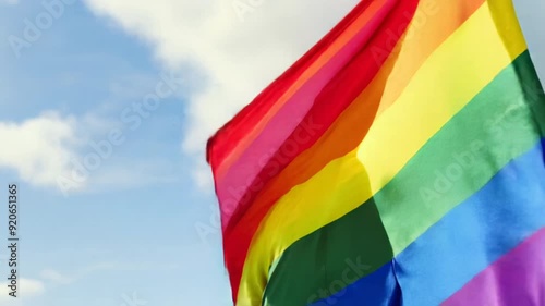 Bearded man in sunglasses holding rainbow flag