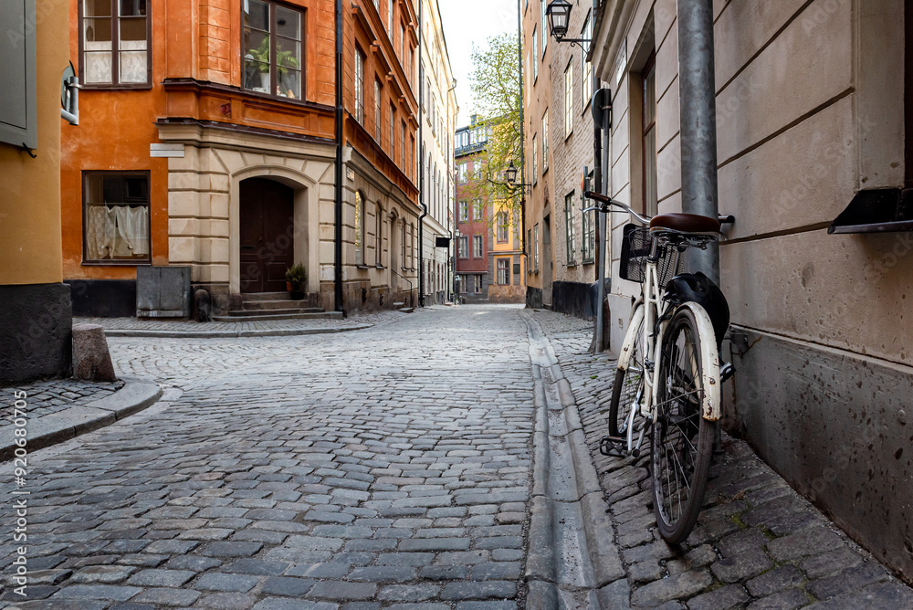 Sweden quaint cobblestone street in picturesque Gamla Stan, Stockholm's oldest neighborhood. Parked bicycles lean against the colorful plaster buildings. Sweden quaint cobblestone street in picturesque Gamla Stan, Stockholm's oldest neighborhood. Parked bicycles lean against the colorful plaster buildings.