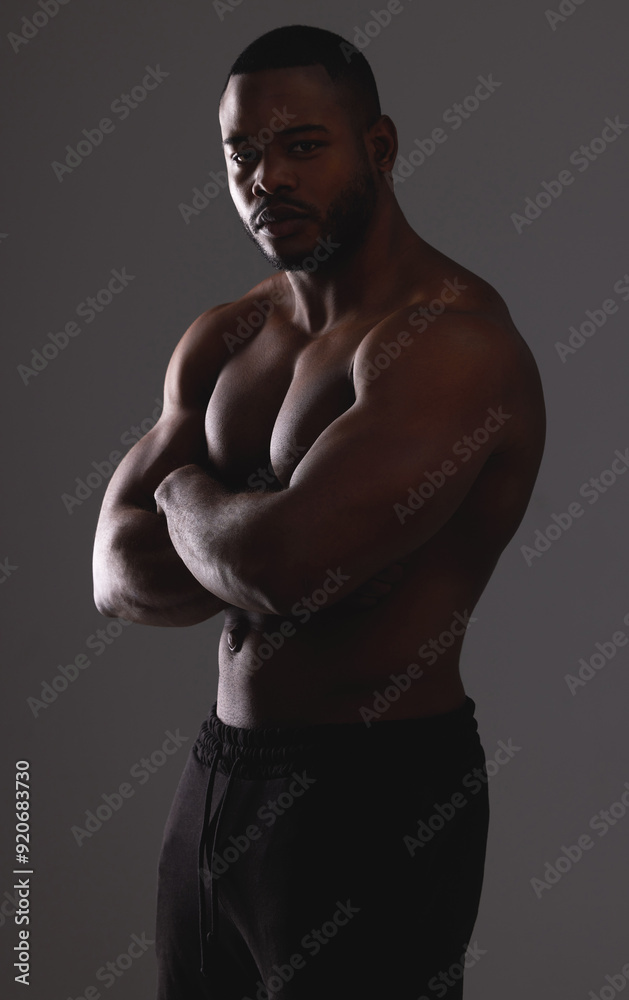 Fototapeta premium Man, arms crossed and muscle in studio for fitness results, body builder and strong on gray background. Male person, flex and athlete for power of shirtless skin, exercise and topless for workout