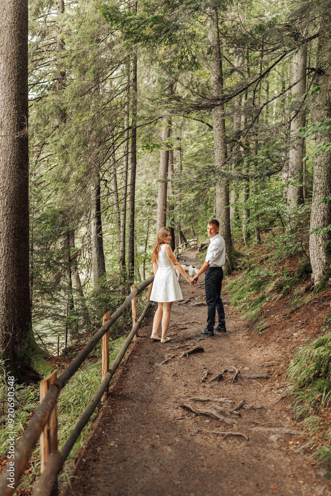 Fototapeta premium A couple is standing on a path in a forest, holding hands