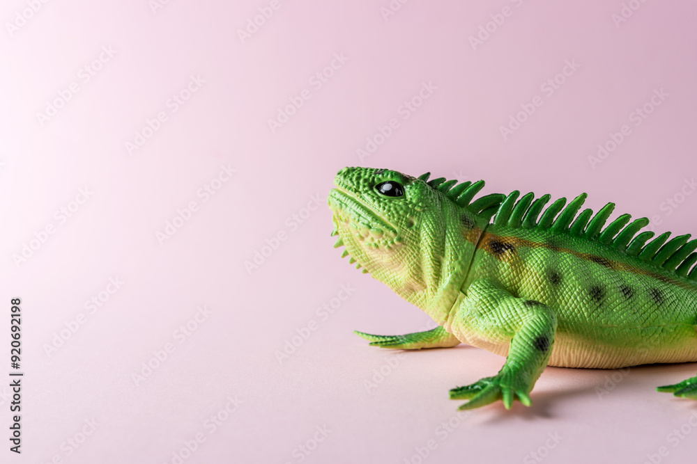 Obraz premium Green lizard toy on pastel pink background. Minimal art concept.
