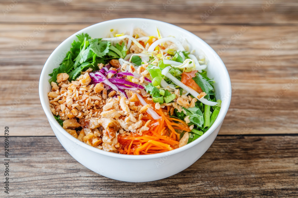 Fresh Vietnamese noodle bowl with vegetables, herbs, and peanuts on rustic wooden background Fresh Vietnamese noodle bowl with vegetables, herbs, and peanuts on rustic wooden background