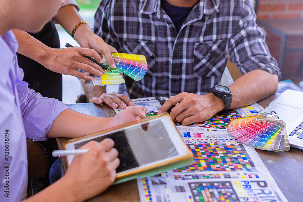 Worker checking print quality of media graphics proof print and color tone in printing industry. Selected focus Worker checking print quality of media graphics proof print and color tone in printing industry. Selected focus