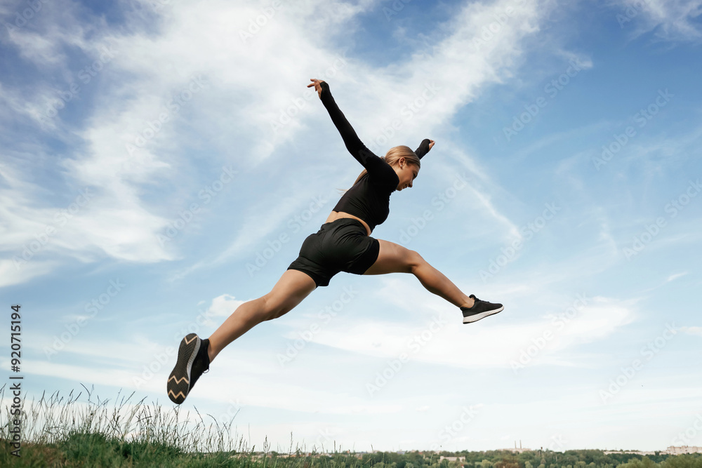Jumping against the sky. Beautiful fitness woman in sport clothes is outdoors Jumping against the sky. Beautiful fitness woman in sport clothes is outdoors