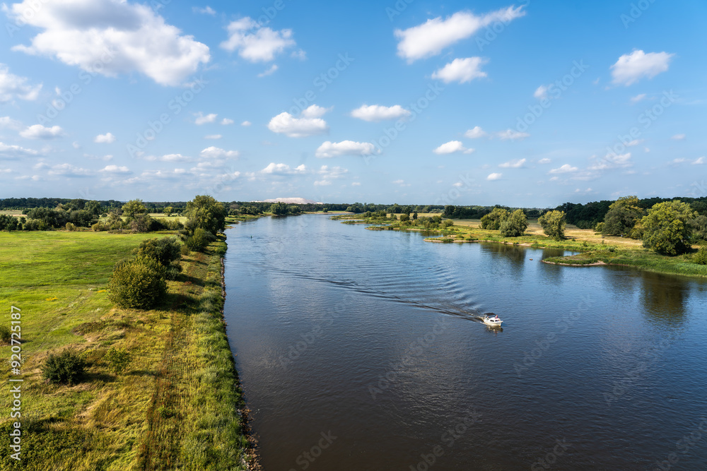 Tranquil river landscape with boat, lush greenery, and blue sky
