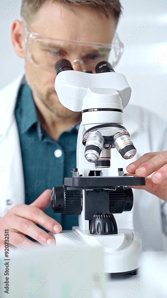 Man scientist with protective glasses using microscope in laboratory. Microbiology science concept Man scientist with protective glasses using microscope in laboratory. Microbiology science concept