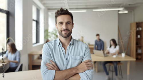 Portrait of a handsome man standing with his arms crossed in a modern office room.