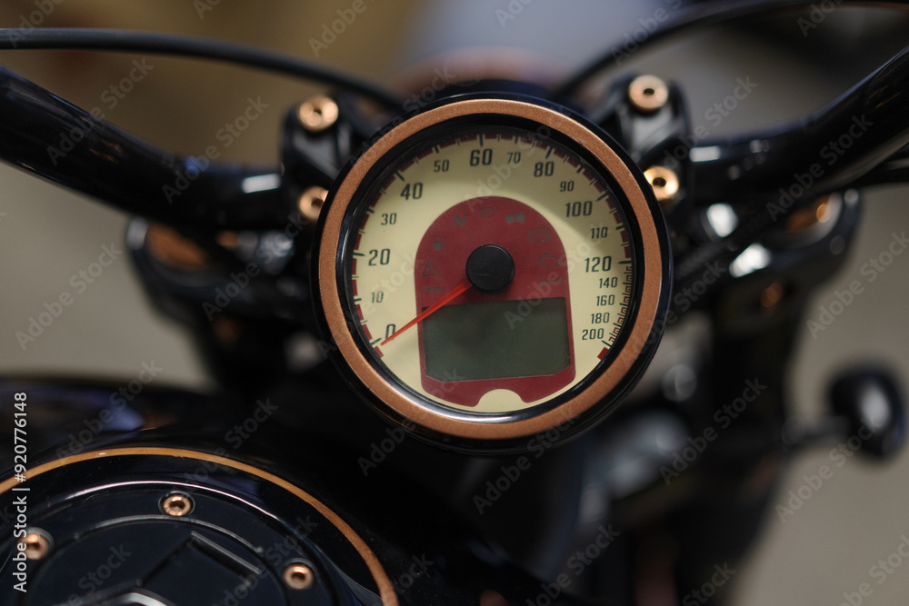 A close-up view of a motorcycle's speedometer. The speedometer is mounted on the handlebars of the bike. The gauge is positioned in the center of the image. A close-up view of a motorcycle's speedometer. The speedometer is mounted on the handlebars of the bike. The gauge is positioned in the center of the image.