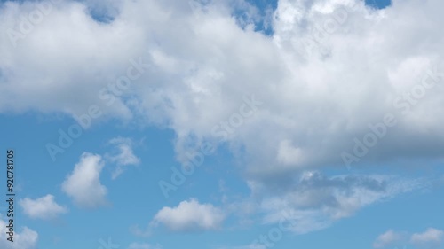 Time lapse of white fluffy disappearing clouds moving in the blue sky. Natural background, 4K resolution.