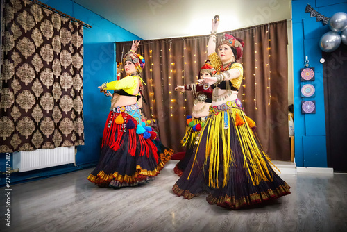 Four women in colorful, traditional costumes dance in an indoor setting, showcasing their vibrant artistry