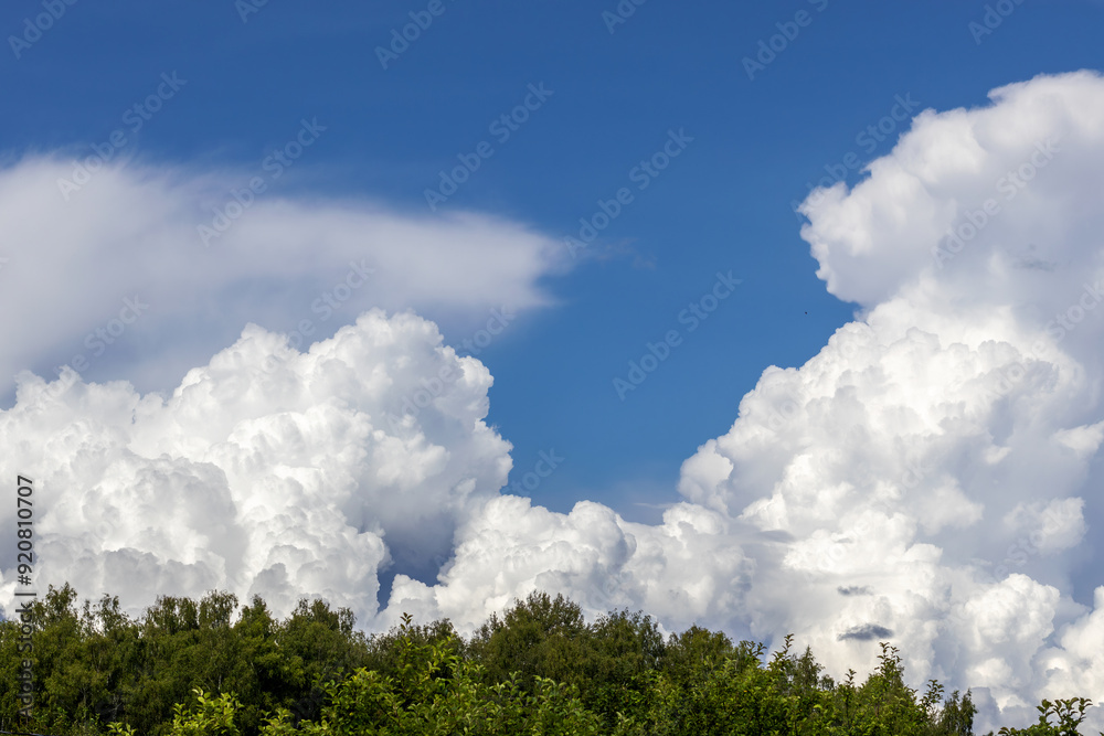 Lush big cumulus clouds in blue sky above forest Lush big cumulus clouds in blue sky above forest