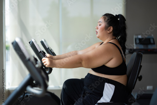 cycling Exercise. beautiful young chubby overweight woman wearing sporty fitness clothes doing exercise indoors at gym fitness sport club, body and health care