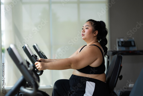 cycling Exercise. beautiful young chubby overweight woman wearing sporty fitness clothes doing exercise indoors at gym fitness sport club, body and health care