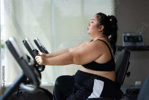 cycling Exercise. beautiful young chubby overweight woman wearing sporty fitness clothes doing exercise indoors at gym fitness sport club, body and health care