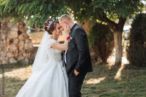 A bride and groom are kissing each other's cheeks in a garden