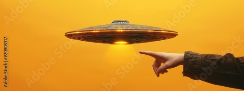  A hand points to a flying saucer in the sky, sunlight filtering through clouds behind
